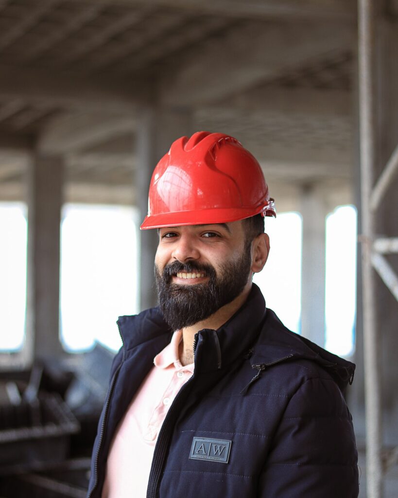 Smiling skilled worker in a red hard hat on a job site