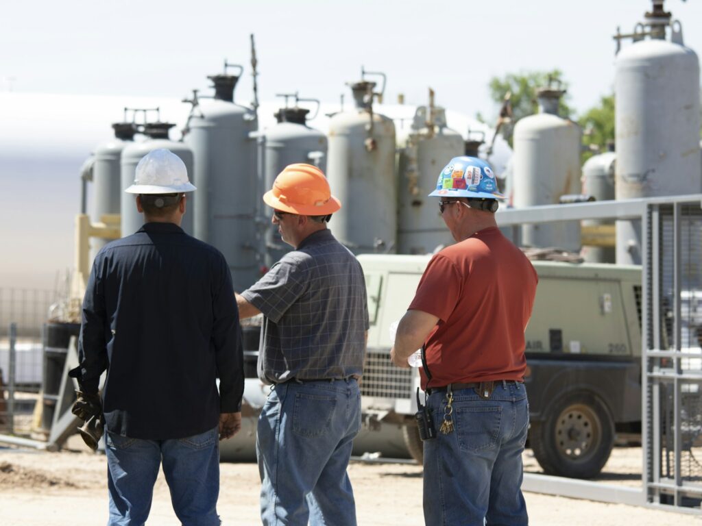 Site supervisor and workers in hard hats reviewing work at an industrial site