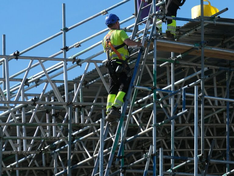 Construction workers in hard hats and safety vests on scaffolding